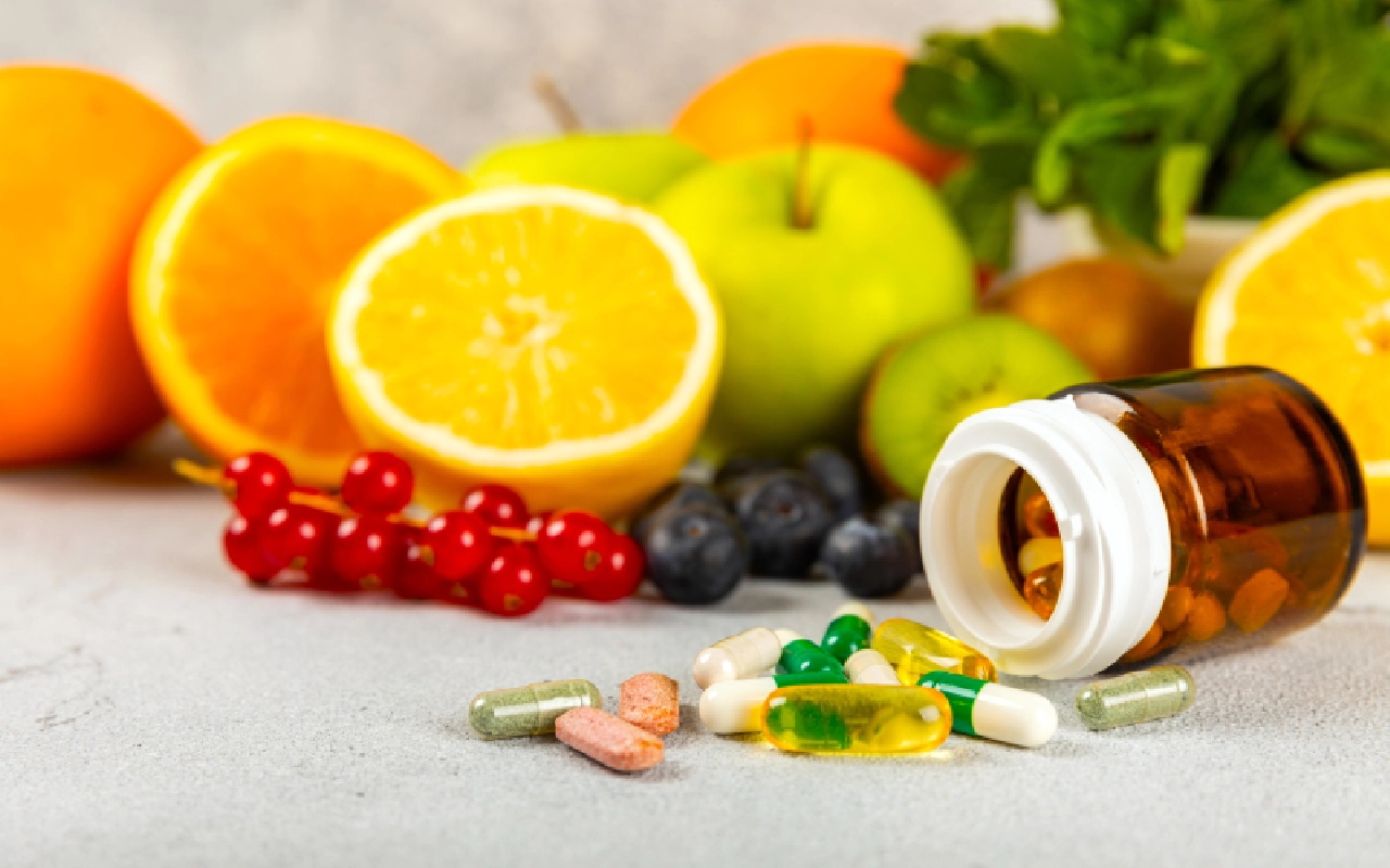 A table topped with fruits and pills next to it.