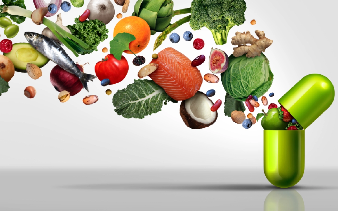 A green pill bottle filled with lots of fresh fruits and vegetables.