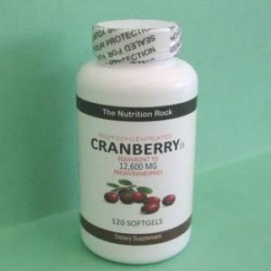 Cranberry supplement softgels bottle on green background.