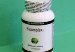 B Complex vitamin bottle on green background.
