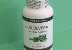 Aloe vera capsules bottle on green background.