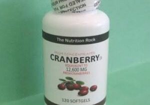 Cranberry supplement softgels bottle on green background.