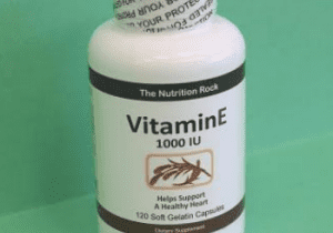 Vitamin E supplement bottle on green background.