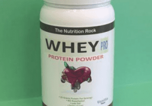Whey protein powder container on green background.